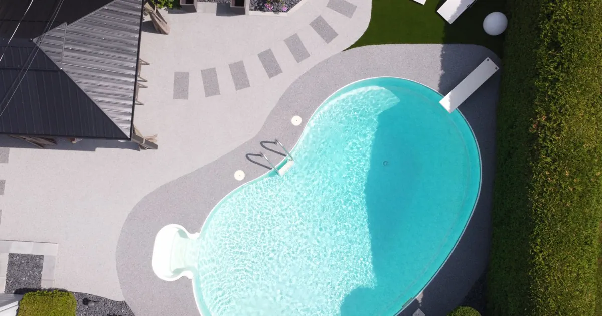 Contour de piscine aménagé avec parcours, mobilier et surface de caoutchouc
